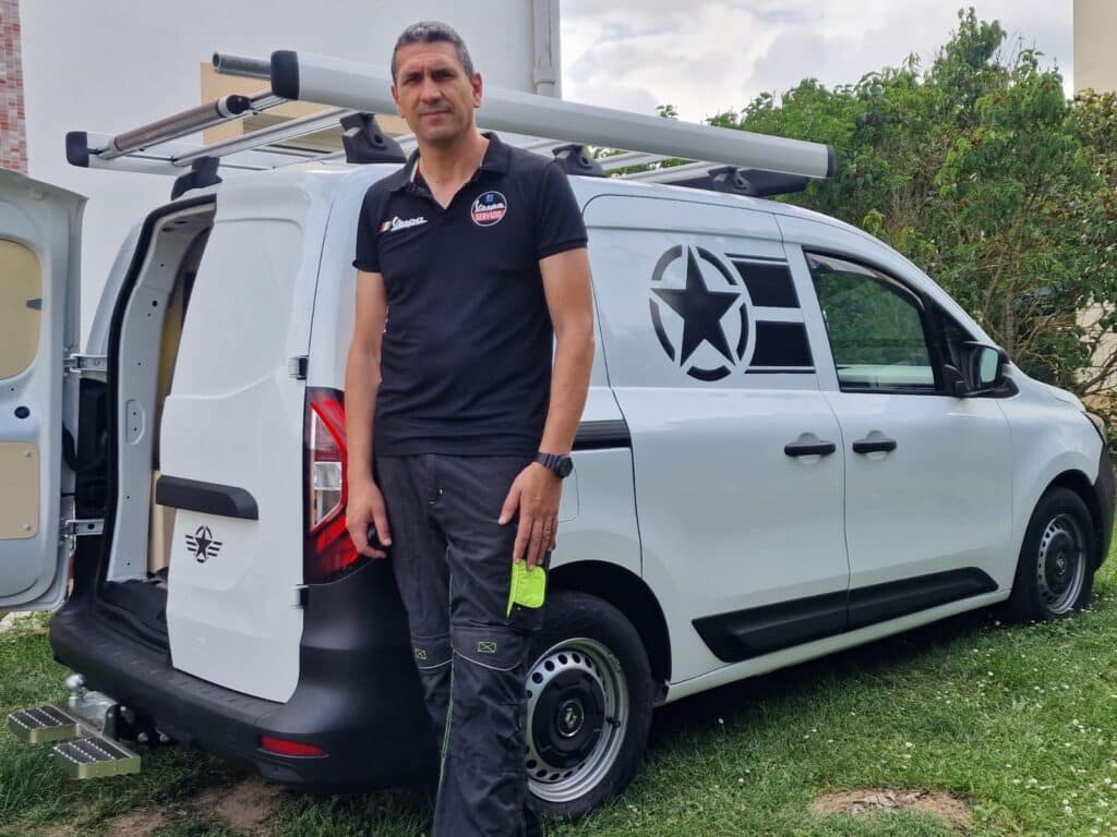Technicien Vespa Servizio et son fourgon utilitaire blanc Technicien en polo Vespa Servizio devant son fourgon utilitaire blanc avec échelles et logo d'étoile.